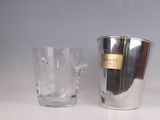a silver ice bucket and a clear glass on a table