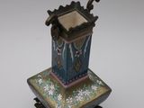 a small blue vase on a stand on a white surface