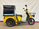 a yellow scooter that is parked in front of a white wall