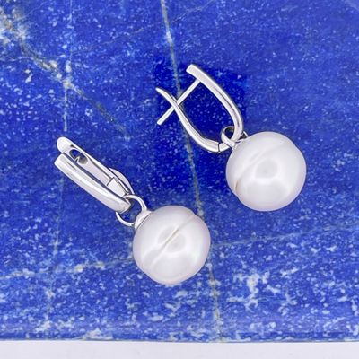 a pair of white pearl earrings on a blue marble surface