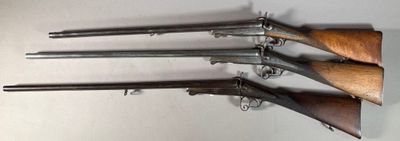 five old guns mounted on a wall in a room