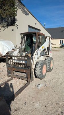 a picture of a skid steer loader parked in front of a building