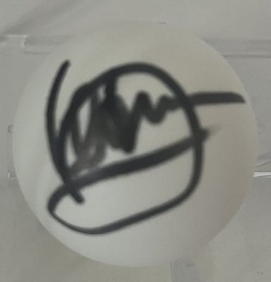 une boule blanche sur laquelle est dessiné un motif, dans une boîte transparente