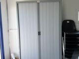 a room with a bed, a desk, a chair, and a refrigerator
