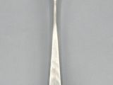 silver plated spoon with a leaf design on it on a gray surface