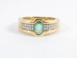 gros plan d'une bague en or avec une pierre verte et des diamants