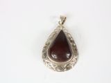 a close up of a silver pendant with a brown stone in it