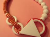 a red and white necklace with a white triangle on it