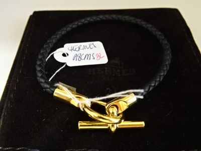 une boîte noire avec un bracelet en or et une étiquette accrochée dessus