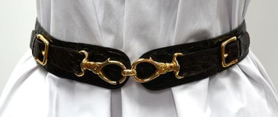 a woman wearing a black belt with gold buckles on it