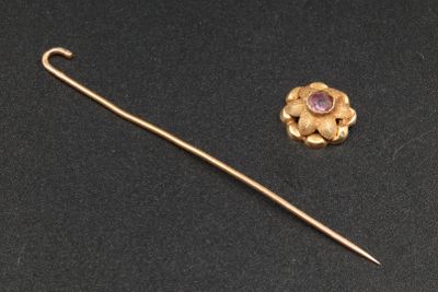 a close up of a gold pin with a purple stone on it
