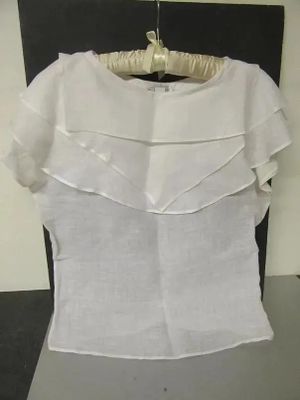 a white top with ruffles on it on a hanger