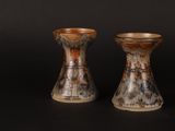 two vases that are sitting on a black surface