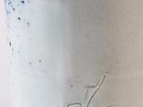 a close up of a white and blue vase on a table