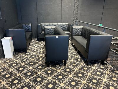 un canapé noir et deux fauteuils noirs dans une pièce