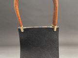 a black leather purse with a wooden handle