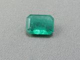 une pierre d'émeraude verte sur une surface grise