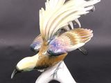 a figurine of a bird that is sitting on a stand