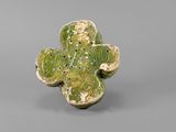 a close up of a green flower shaped object on a gray surface