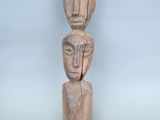 une sculpture en bois représentant un homme, surmontée d'un visage