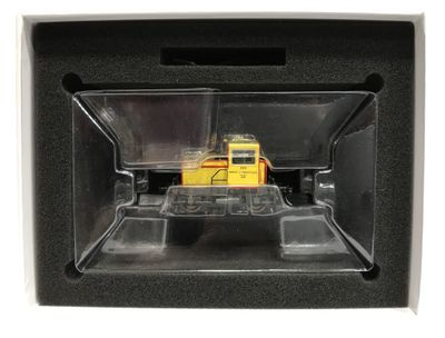 un petit camion jaune dans une boîte noire posée sur une surface blanche