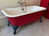 une baignoire rouge et blanche dans une salle de bains dont la porte est rouge