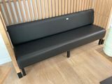 a black bench in a room with a wooden wall behind it