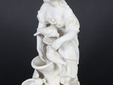 a white statue of a woman holding a child on a rock