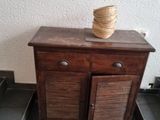 a small wooden cabinet with a basket on top of it