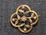 Gros plan sur une broche en or ornée de perles
