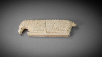 une image représentant un morceau d'ivoire sculpté sur une surface grise