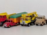 many toy trucks lined up in a row on a white surface
