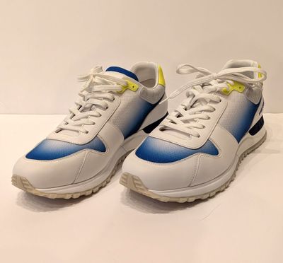 une paire de baskets blanches et bleues posées sur une surface blanche