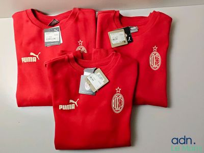 trois t-shirts rouges avec des logos blancs, posés sur une table