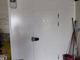une porte blanche dans une pièce où se trouvent des cartons et des balais