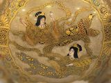 a gold vase with a picture of a woman and a man on it