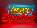 une enseigne au néon rouge et bleue sur laquelle on peut lire « aprtrol » et « spritz »