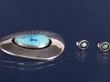 trois bijoux posés sur une surface bleue