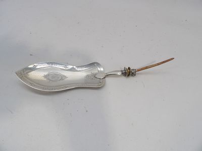 une cuillère en argent avec un manche en bois posée sur une surface blanche