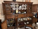 a wooden china cabinet with a lot of dishes on top of it