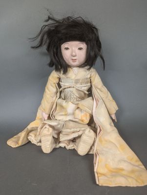 une vieille poupée aux longs cheveux noirs, assise par terre