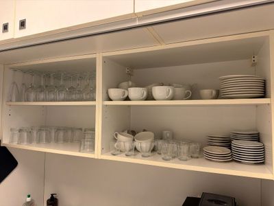 des étagères remplies de vaisselle et de verres dans une cuisine équipée de placards blancs