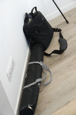 un sac noir et une canne posés par terre près d'un mur