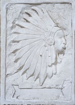 relief of a man with a feather headdress on a stone wall