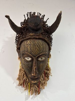 une image représentant un masque en bois muni de cornes sur la tête