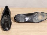 pair of black shoes on a wooden surface with a white background