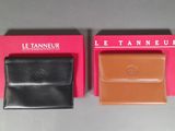 two black and brown leather wallets sitting on top of a pink box