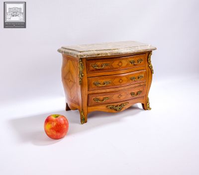 une petite commode avec un plateau en marbre, à côté d'une pomme