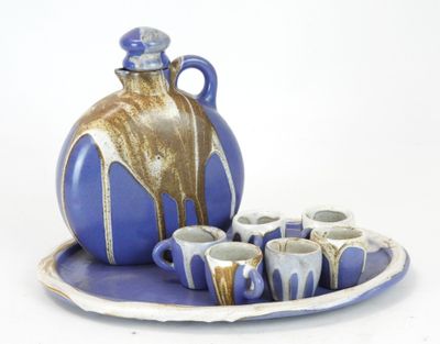 a blue and white plate with cups and a jug on it