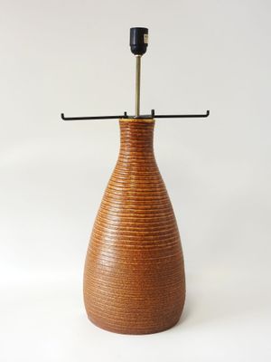 un vase marron avec une anse noire sur fond blanc